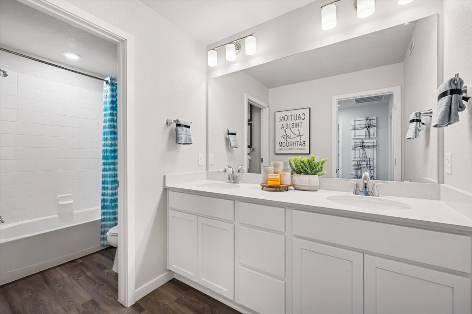 A bathroom with a tub sink and a mirror.
