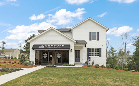 A white building with a sign on it with Southfork Ranch in the background.