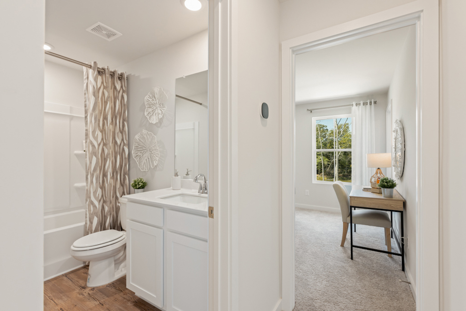 A bathroom with a sink toilet and a mirror.