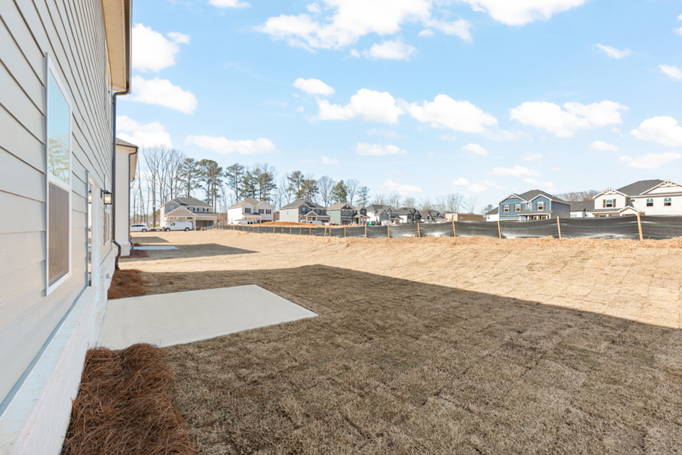 A dirt field with houses in the background.