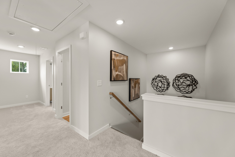 A room with a white wall and a white staircase.