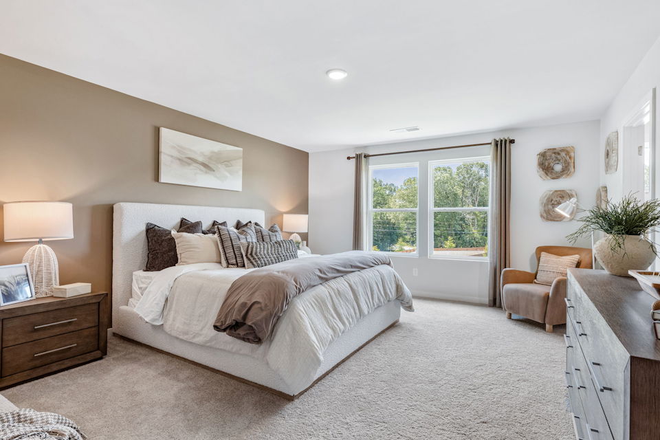 A bedroom with a bed and a chair.