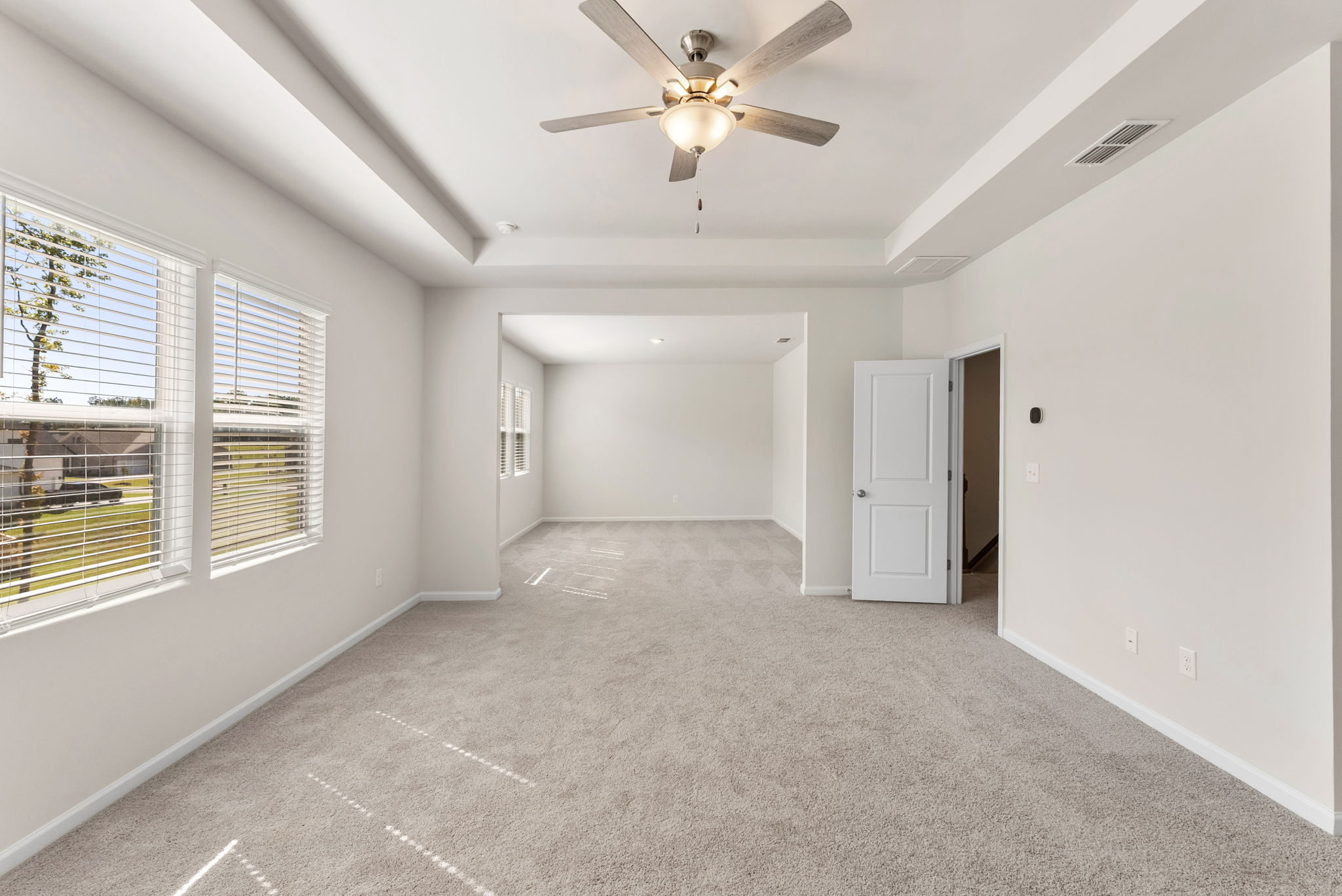 A room with a ceiling fan and a door.