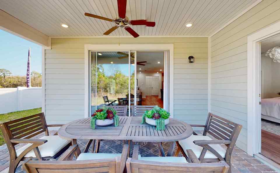 A dining table with chairs and a fan in a room with a large window.