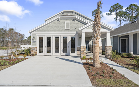 A white house with a tree in front of it.