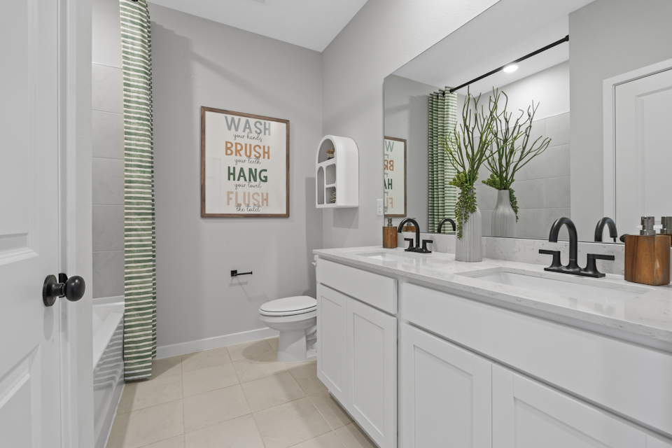 A bathroom with a sink toilet and a mirror.