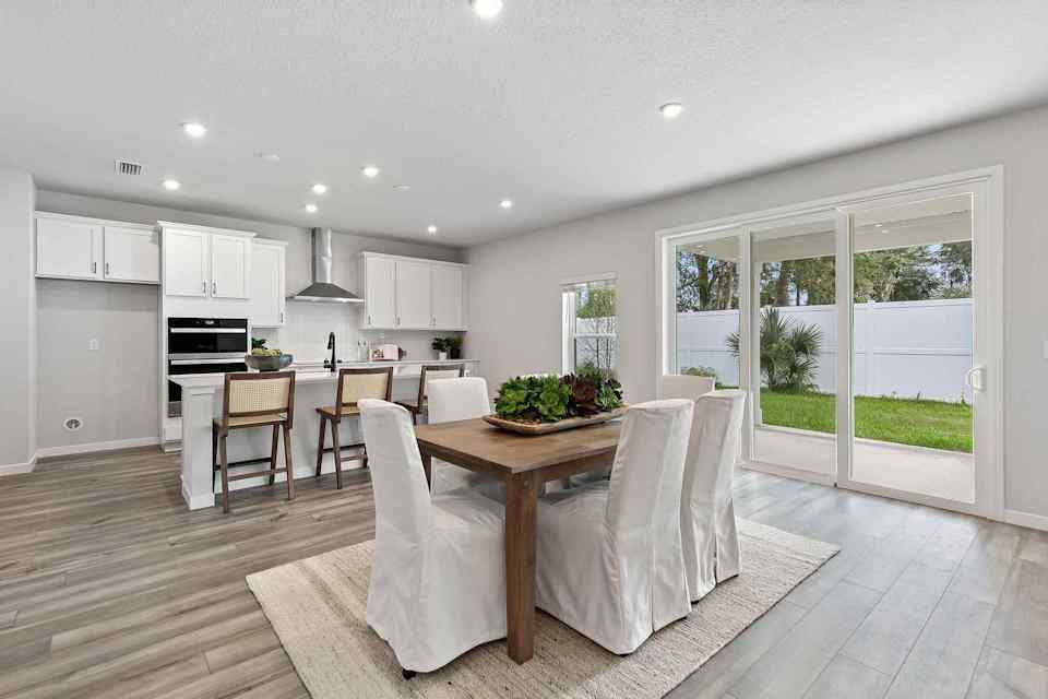 A kitchen with a dining table and chairs.
