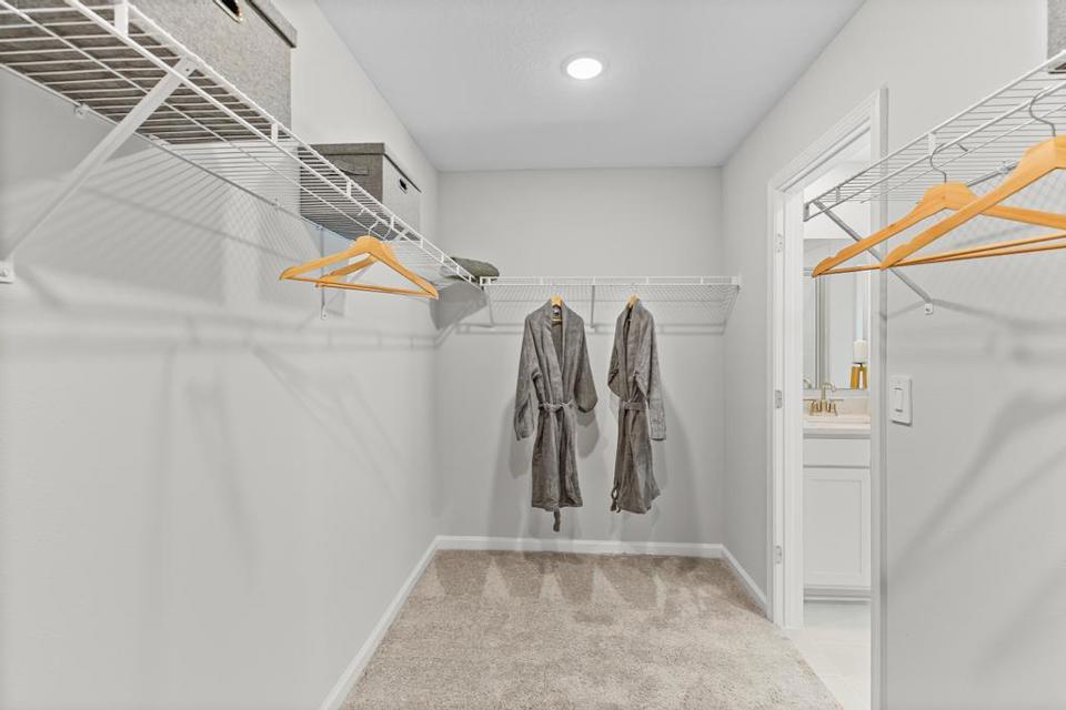 A room with a staircase and clothes on the wall.