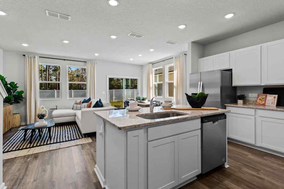 Davor Model Paired Home White Kitchen Island overlooking living room at The Landings at Pecan Park