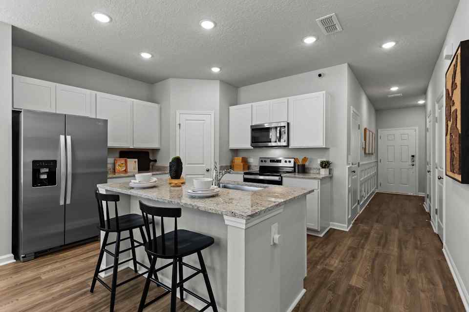 Davor Model Paired Home Kitchen with White Cabinets and Stainless Steel Appliances at The Landings at Pecan Park