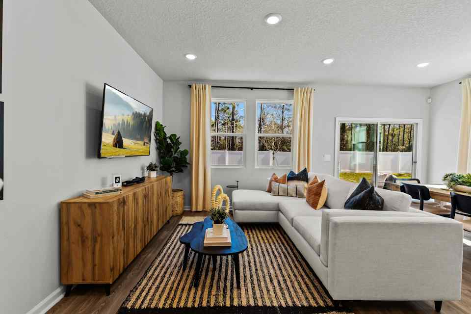 Davor Model Paired Home Living Room with Cream Couch and Black Table and Double Window at The Landings at Pecan Park