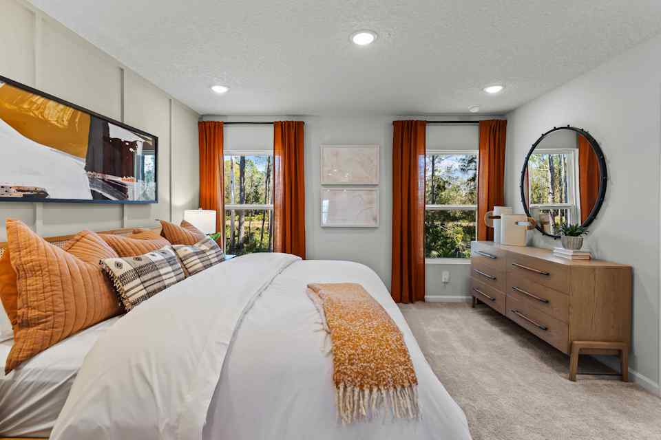 Davor Model Paired Home Primary Bedroom with Bed, Dresser, and 2 Windows at The Landings at Pecan Park