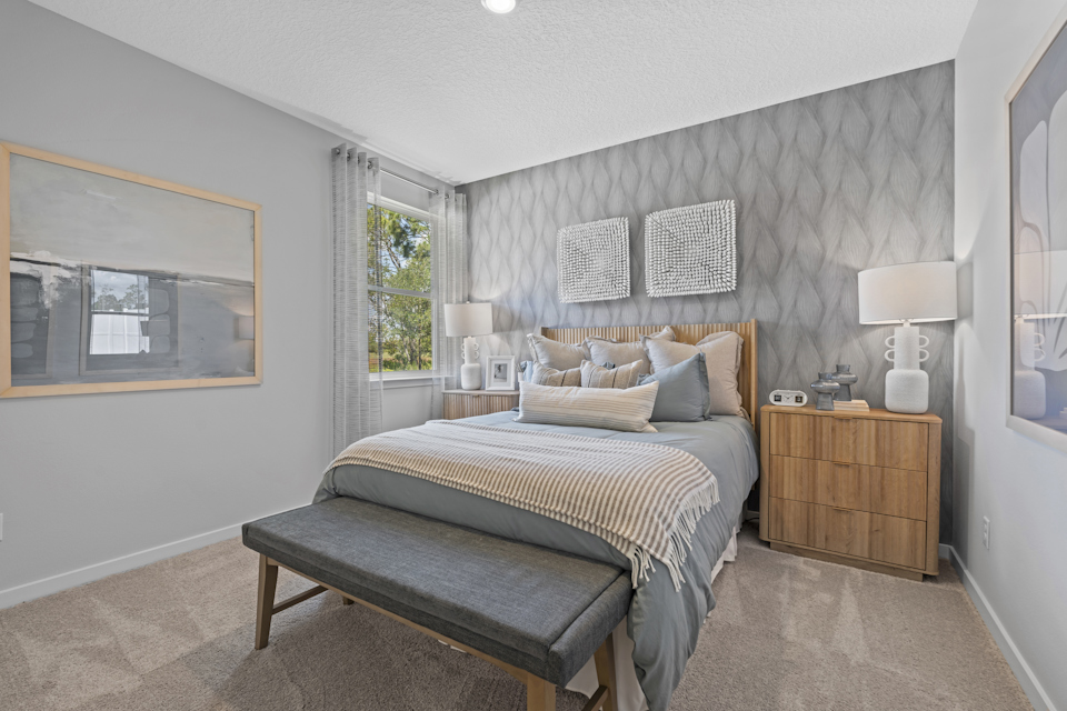 Coronado Model Home Guest Bedroom with Bed and Bench at Reserve East in Flagler Beach