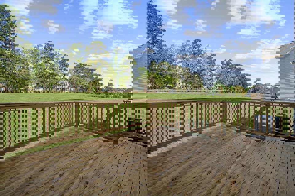 A wooden deck with a fence and trees in the background.