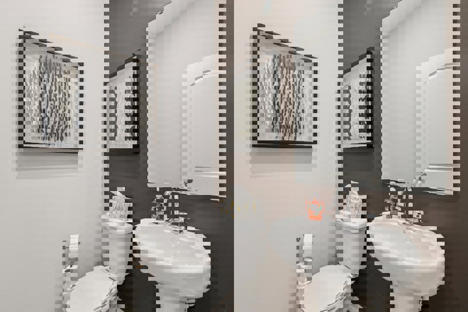 A bathroom with a sink toilet and a mirror.