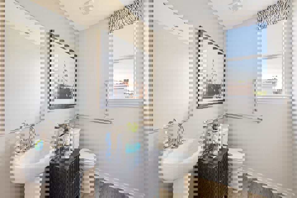 A bathroom with a sink toilet and a mirror.