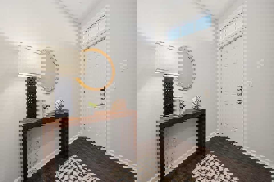 A room with a mirror and a table with a lamp on it.