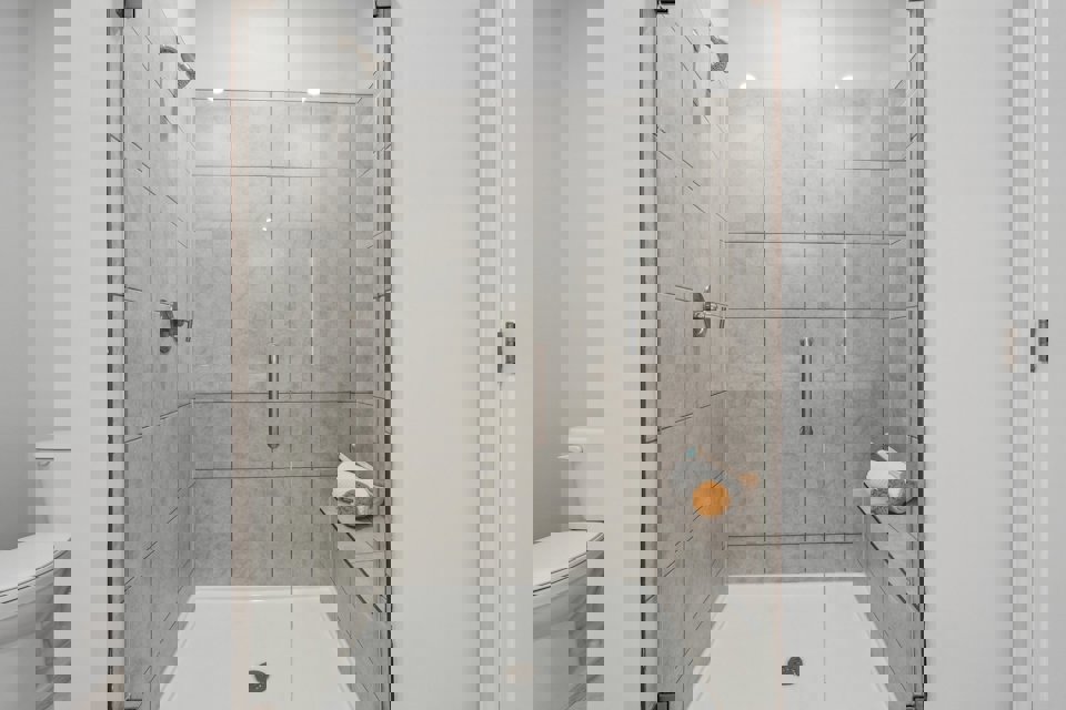 A bathroom with a shower unit and toilet.