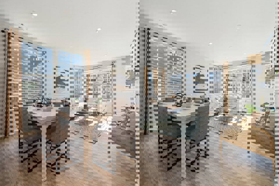 A large living room with a large dining table and a large window.