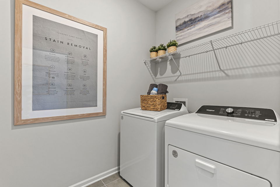 A white laundry room with a white wall and a white radiator.