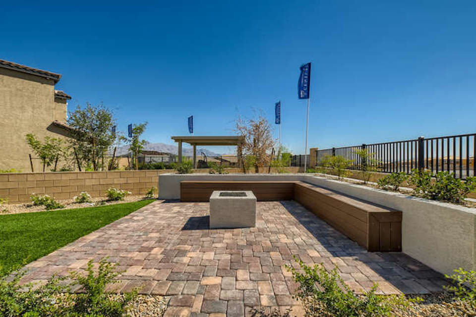A brick walkway with a bench and a fence and a building.