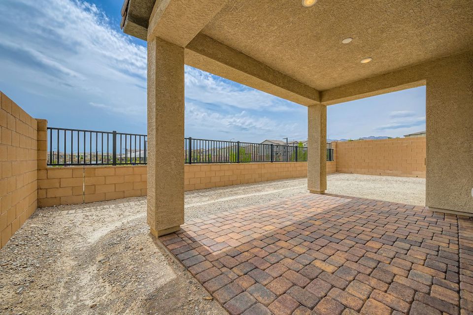A stone walkway with a fence and a building in the background.