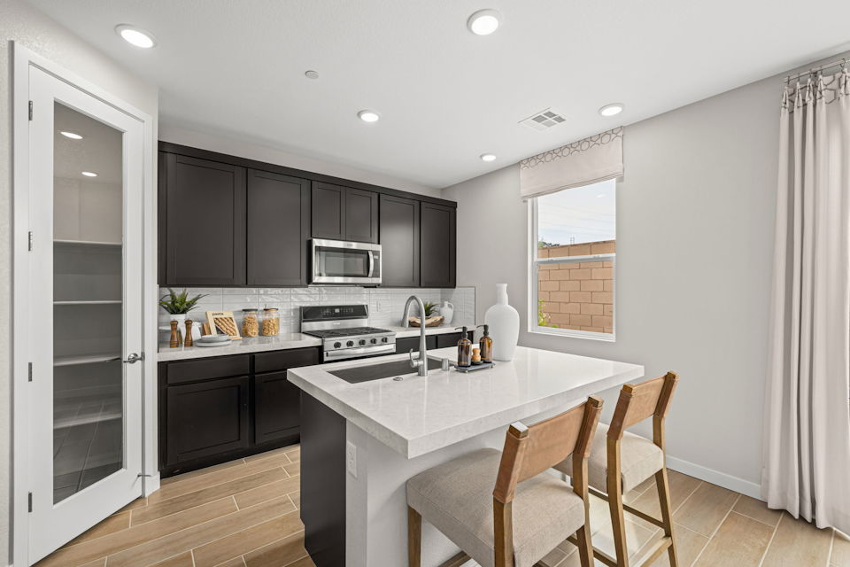 A kitchen with a white counter top and black cabinets.