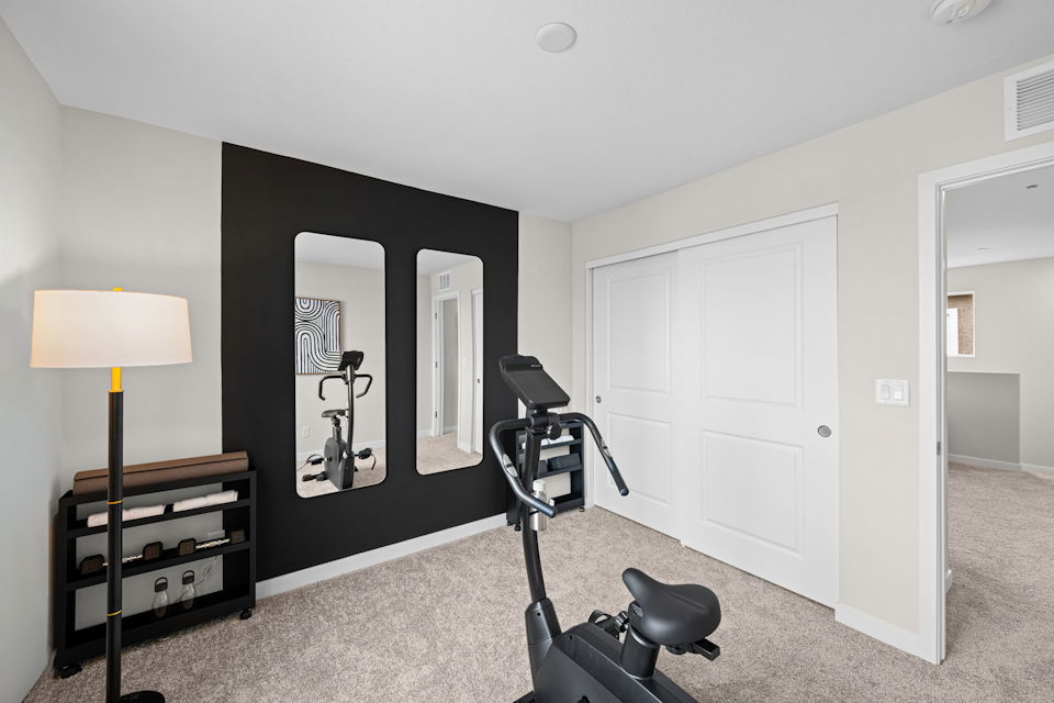 A room with a black chair and a lamp.