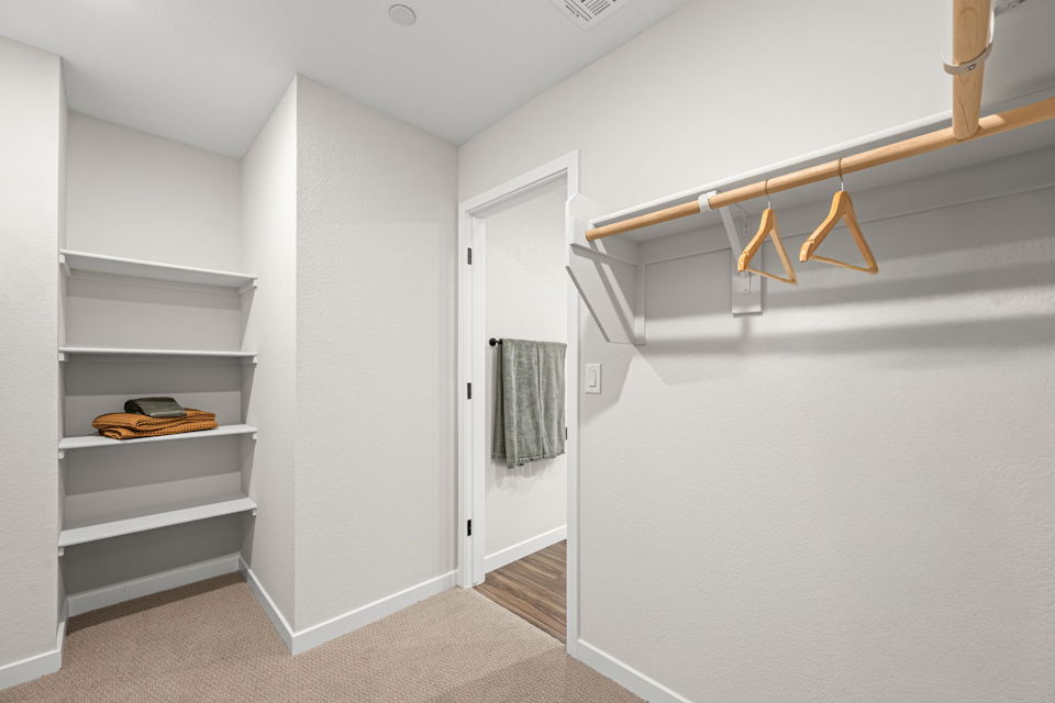 A white room with a white door and a white shelf with a towel from it.