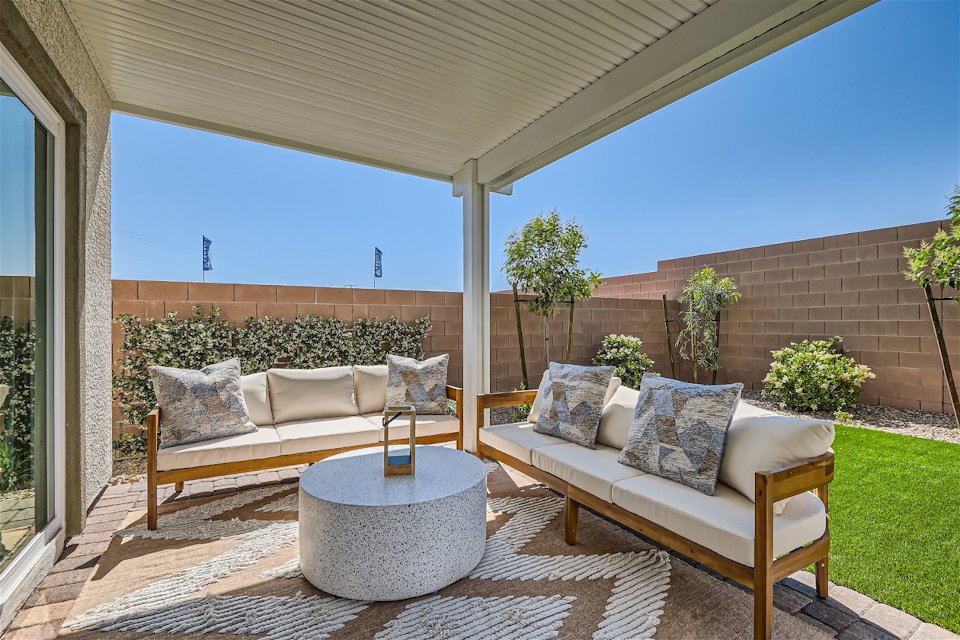 A patio with a couch and a table with a potted plant.