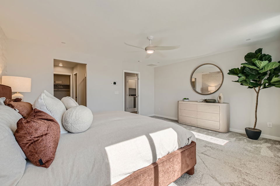 A bedroom with a bed and a plant.