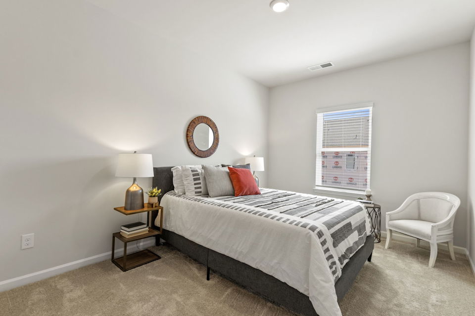 A bedroom with a bed and a chair.