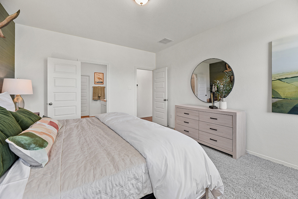 A bedroom with a bed and a mirror.