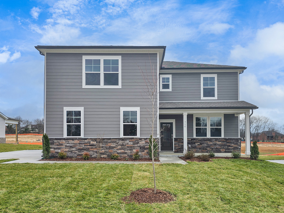A grey house with a stone driveway.