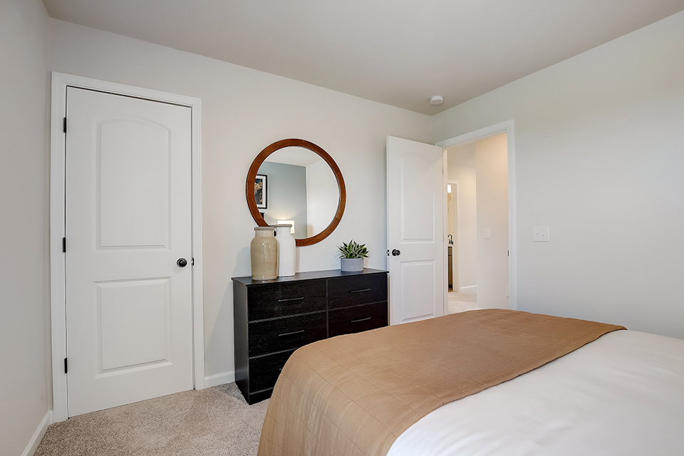 A bedroom with a mirror and dresser.