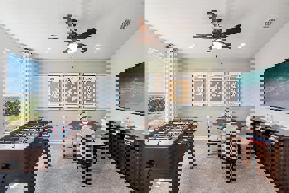 A room with a pool table and chairs and a large fan.