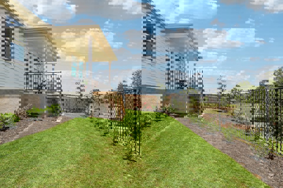 A house with a fence and a lawn in front of it.