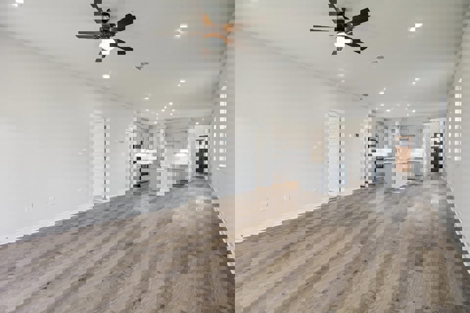 A large empty room with a wood floor and a ceiling fan.