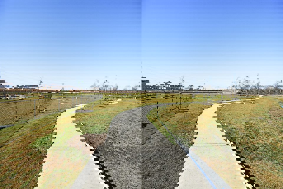 A concrete walkway with grass and trees.