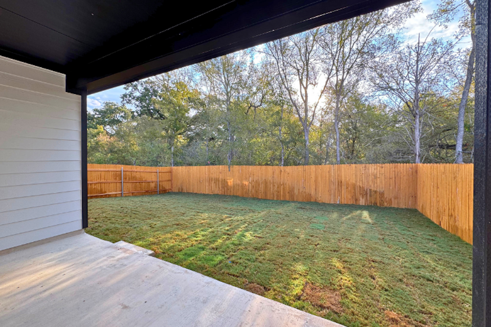 A backyard with a fence and trees.