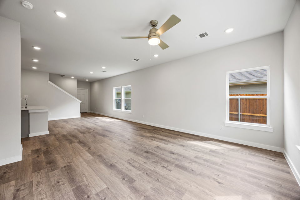 A large empty room with a wood floor and a ceiling fan.