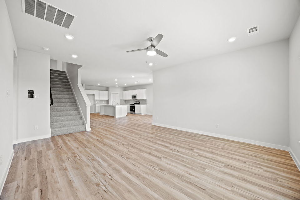 A large empty room with a wood floor and a ceiling fan.