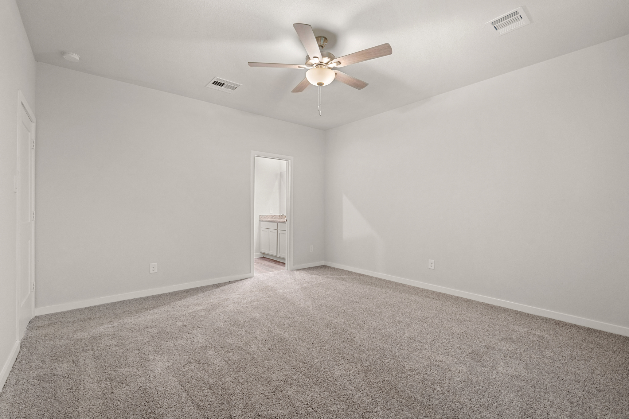 A room with a ceiling fan and a carpet.