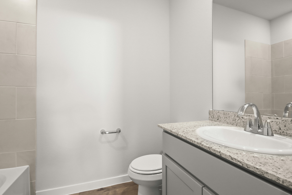 A bathroom with a sink toilet and a mirror.