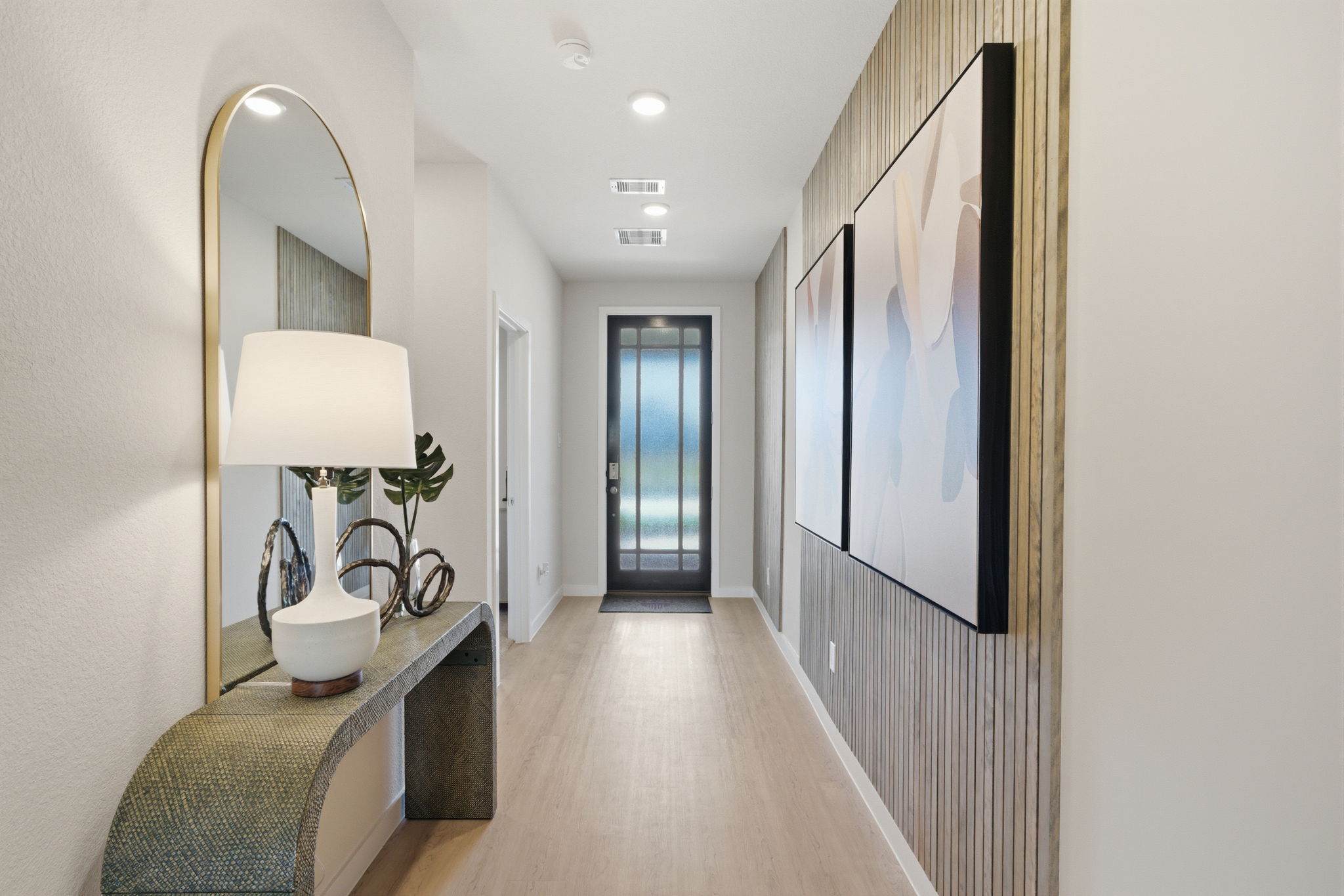 A hallway with a mirror and a lamp.