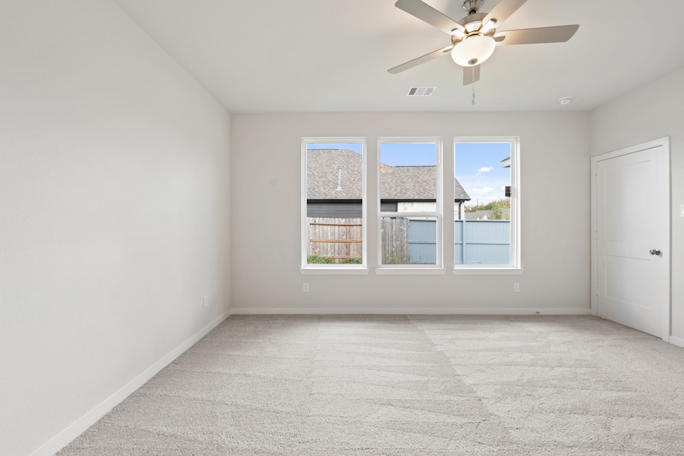 A room with a ceiling fan and a window with a view of the ocean.