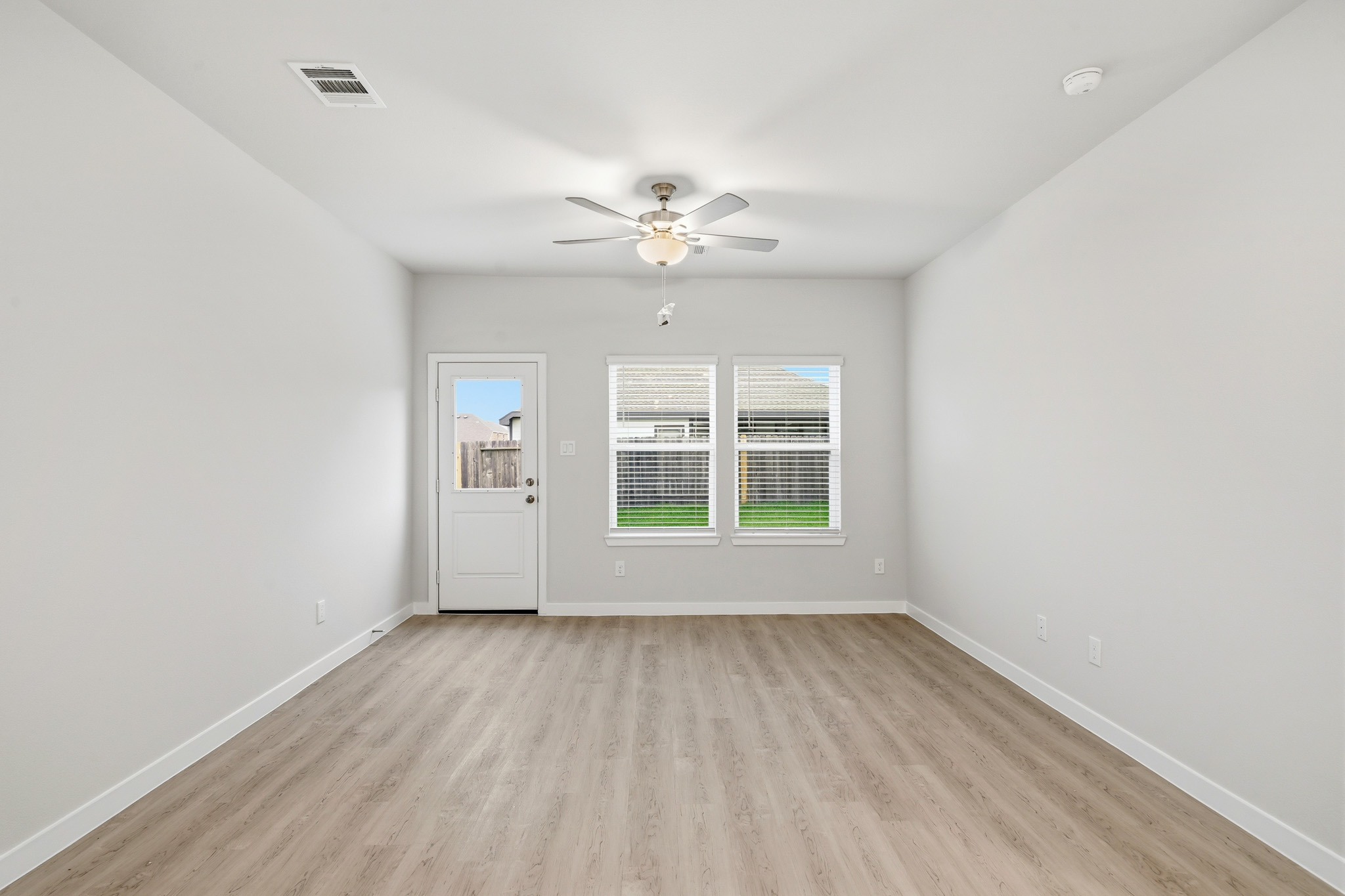 A room with a ceiling fan and a wood floor.