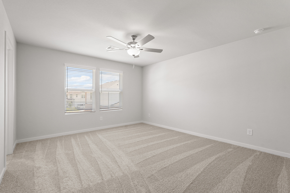 A room with a ceiling fan and a carpet.