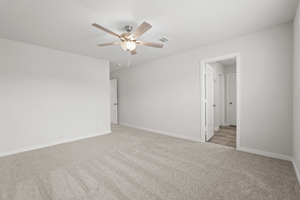 A room with a ceiling fan and white walls.