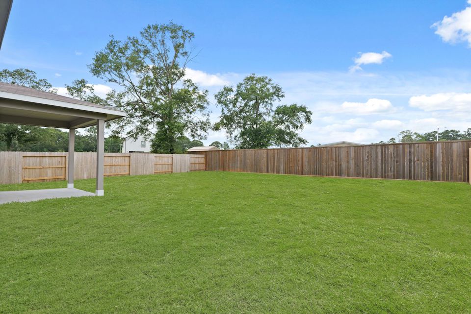 A fenced in yard with a tree and a house in the background.